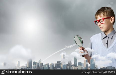 Exploring the world. Cute school boy examining objects with magnifying glass