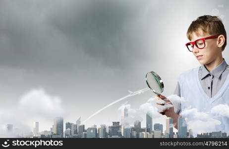 Exploring the world. Cute school boy examining objects with magnifying glass