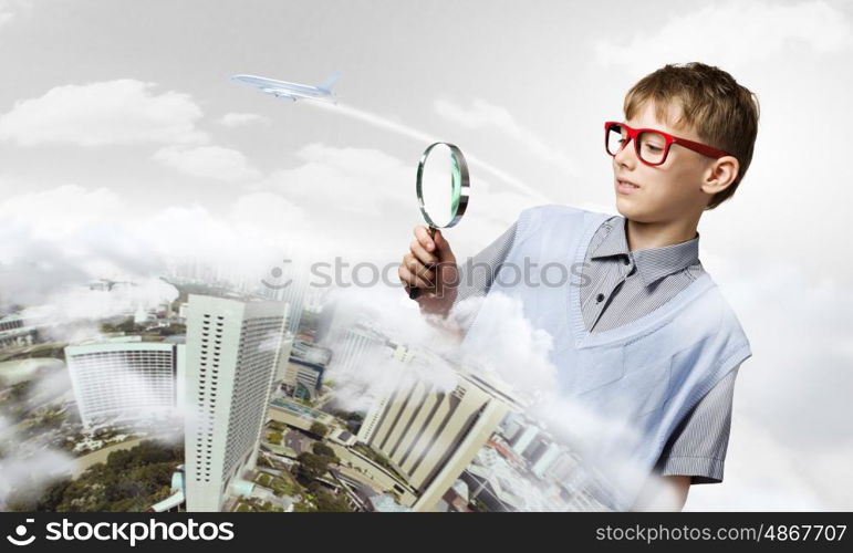 Exploring the world. Cute school boy examining objects with magnifying glass