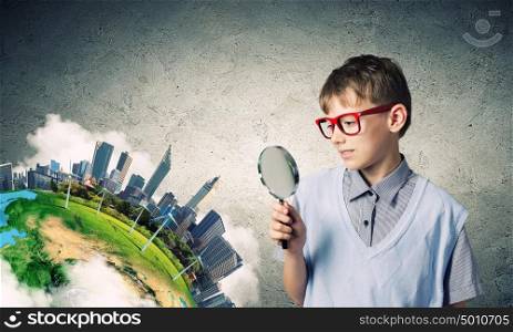 Exploring the world. Cute school boy examining objects with magnifying glass. Elements of this image are furnished by NASA