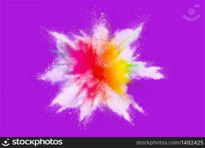 Explosion of colored powder isolated on purple background.