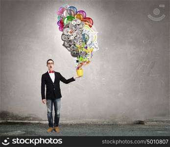 Express your creative individuality. Young man holding yellow small bucket in hand and splashing colorful paint
