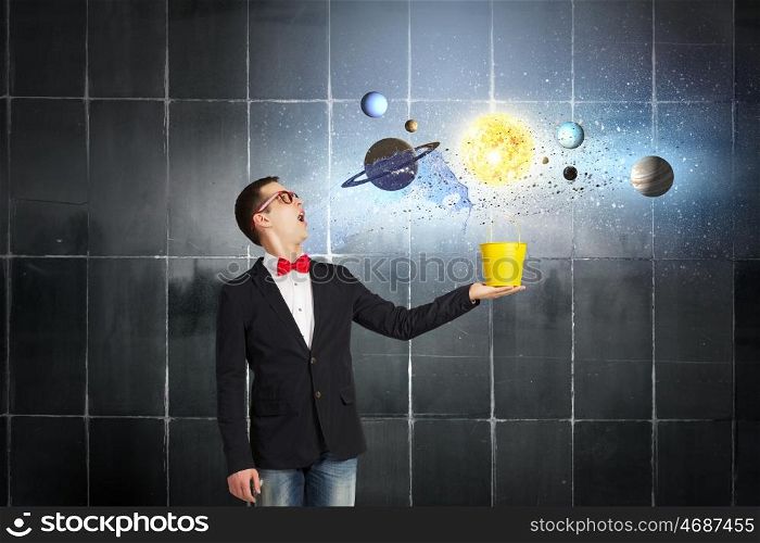 Express your creative individuality. Young man in jacket and red glasses with yellow bucket in hands
