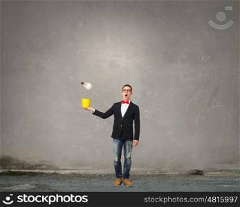Express your creative individuality. Young man in jacket and red glasses with yellow bucket in hands