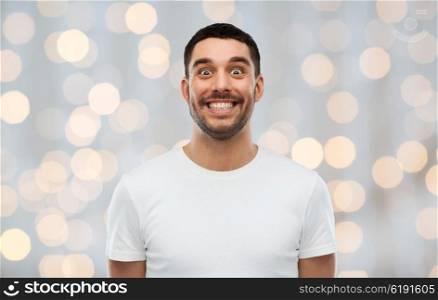 expression, emotions and people concept - man with funny face over holidays lights background