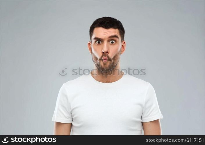 expression, fun and people concept - man with funny fish-face over gray background