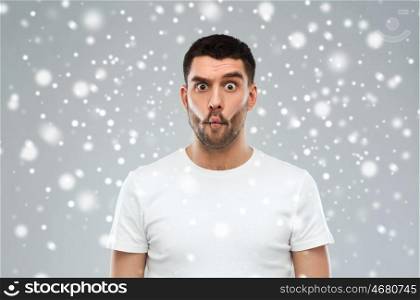 expression, fun, winter, christmas and people concept - man with funny fish-face over snow on gray background