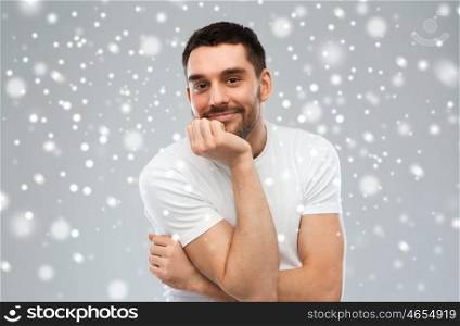expression, winter, christmas and people concept - happy smiling man over snow on gray background