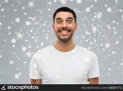 expression, winter, christmas and people concept - man with funny face over snow on gray background