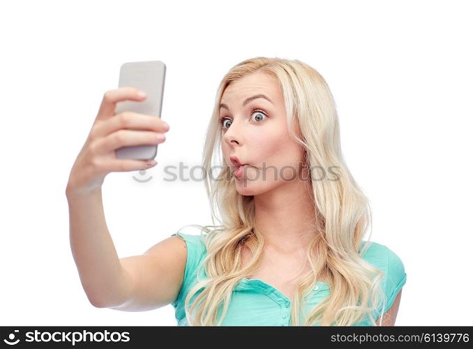 expressions, technology and people concept - funny young woman or teenage girl taking selfie with smartphone and making fish face