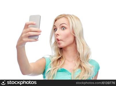 expressions, technology and people concept - funny young woman or teenage girl taking selfie with smartphone and making fish face