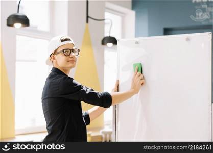 expressive schoolboy cleaning blackboard