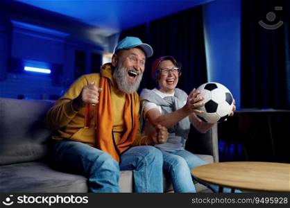 Expressive senior family couple watching football match on tv at home. Elderly husband and wife feeling overjoyed and excited screaming and cheering favorite soccer game. Expressive senior family couple watching football match on tv at home
