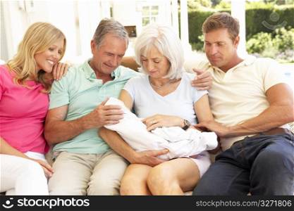 Extended Family Relaxing Together On Sofa With Newborn Baby