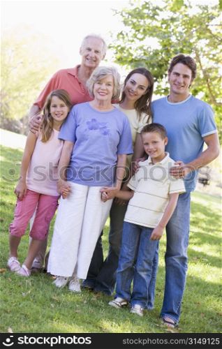 Extended family standing in park holding hands and smiling