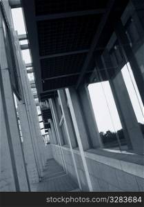 Exterior of building corridor with windows and pillars.
