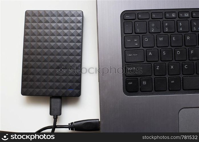 External hard drive connect to laptop computer, transfer or backup data between laptop and hard disk close-up. External hard drive connect to laptop computer, transfer or backup data between laptop and hard disk