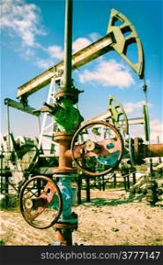 Extraction of oil. Wellhead with valve armature and pump jack. Toned.