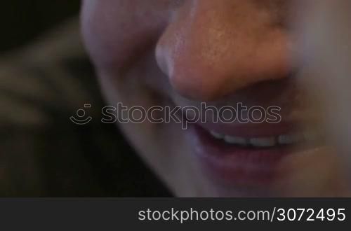 Extreme close-up of a young smiling man. At fisrt focus on his mouth then on the eyes