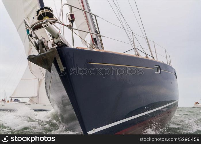 Extreme close up of blue hulled sailing boat, sail boat or yacht at sea with other yachts in the background