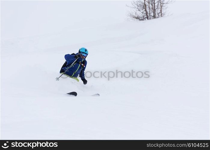 extreme freeride skier skiing on fresh powder snow in forest downhill at winter season