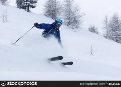 extreme freeride skier skiing on fresh powder snow in forest downhill at winter season