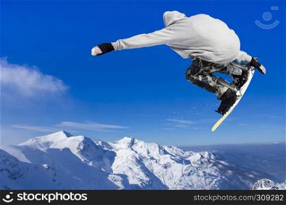 Extreme Jumping Snowboarder at jump above mountains at sunny day