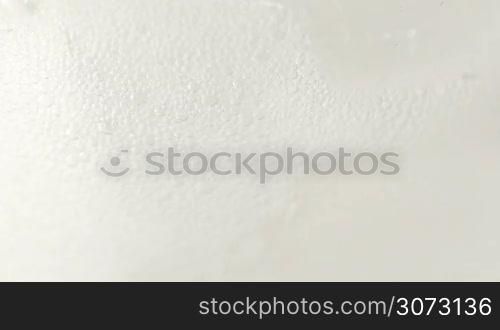 Extreme macro detail of clear soda pouring into glass with ice