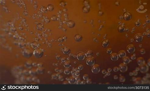 Extreme macro of dark soda bubbles moving
