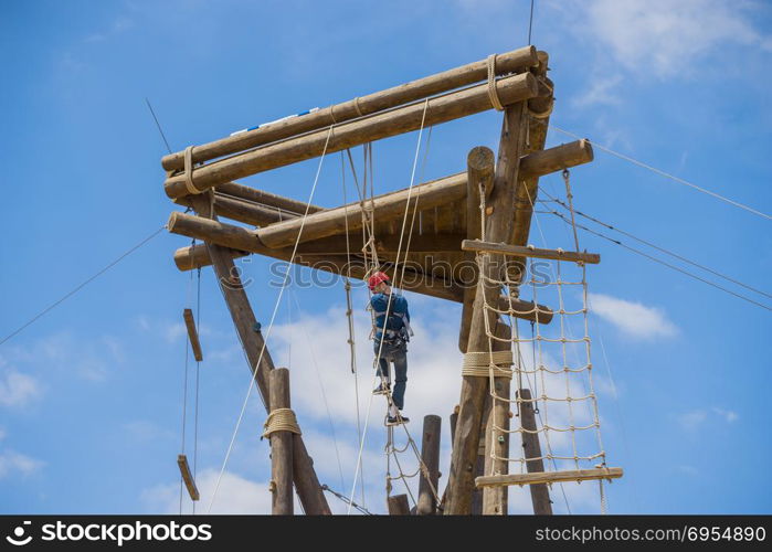 Extreme professional videographer during shooting on climbing tower working under extreme conditions. He has a DSLR camera and an action camera.