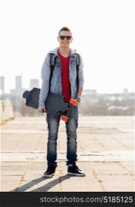 extreme sport and people concept - happy smiling young man or teenage boy with backpack and on longboard in city. happy young man or teenage boy with longboard