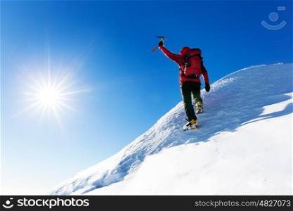 Extreme winter sports: climber reaches the top of a snowy peak in the Alps