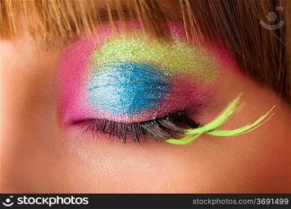 eye close up with colored make up and green long eyelashes