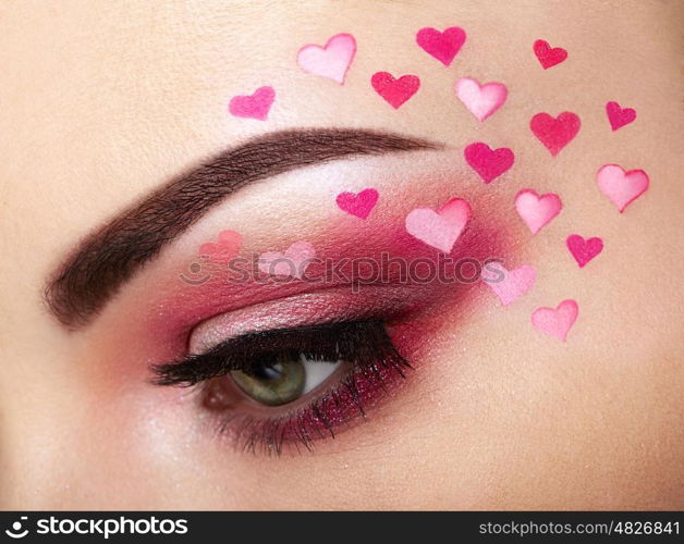 Eye make-up girl with a heart. Valentine's day makeup. Beauty fashion. Eyelashes. Cosmetic Eyeshadow. Makeup detail. Creative woman holiday make-up