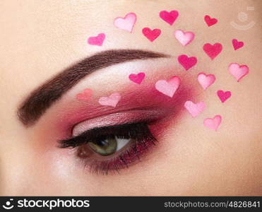 Eye make-up girl with a heart. Valentine's day makeup. Beauty fashion. Eyelashes. Cosmetic Eyeshadow. Makeup detail. Creative woman holiday make-up