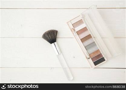 eye shadow and brush on light wooden background. flat lay