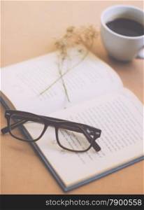 Eyeglasses and book with black coffee , retro filter effect