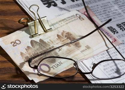 Eyeglasses and Chinese Yuan note on a newspaper