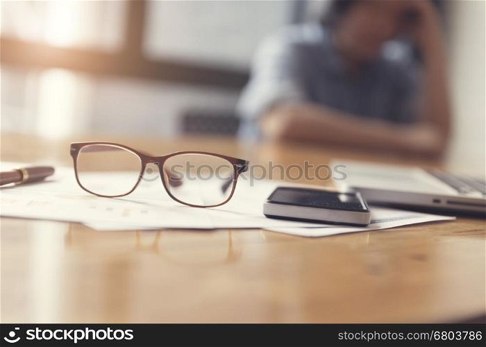 eyeglasses, business document and laptop computer notebook on wooden table, selective focus and vintage tone