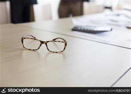 eyeglasses calculator and business document on wooden table