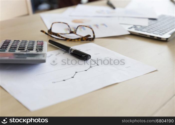 eyeglasses calculator, business document and laptop computer notebook on wooden table