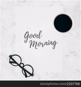 eyeglasses coffee cup good morning text paper white marble textured backdrop