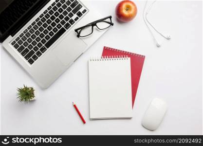 eyeglasses laptop apple earphones colored pencil spiral notepad mouse white desk