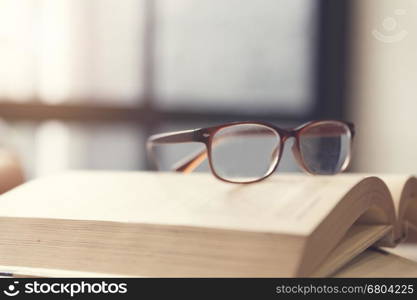 eyeglasses on old book in room, selective focus and vintage tone