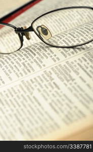 Eyeglasses on the old thick book. A photo close up