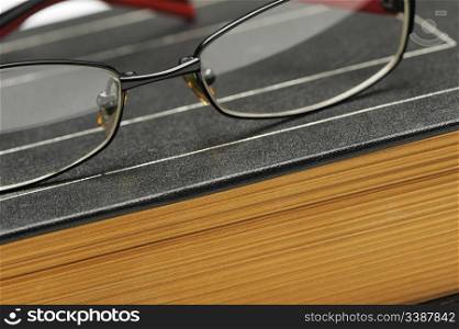 Eyeglasses on the old thick book. A photo close up