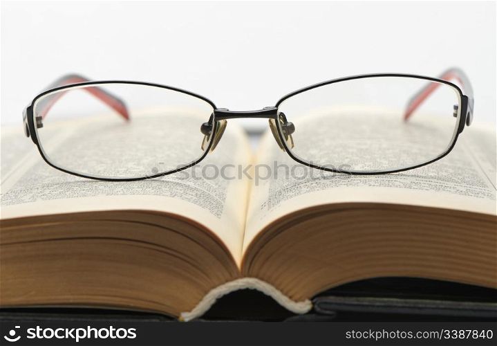 Eyeglasses on the old thick book. Isolated on white background