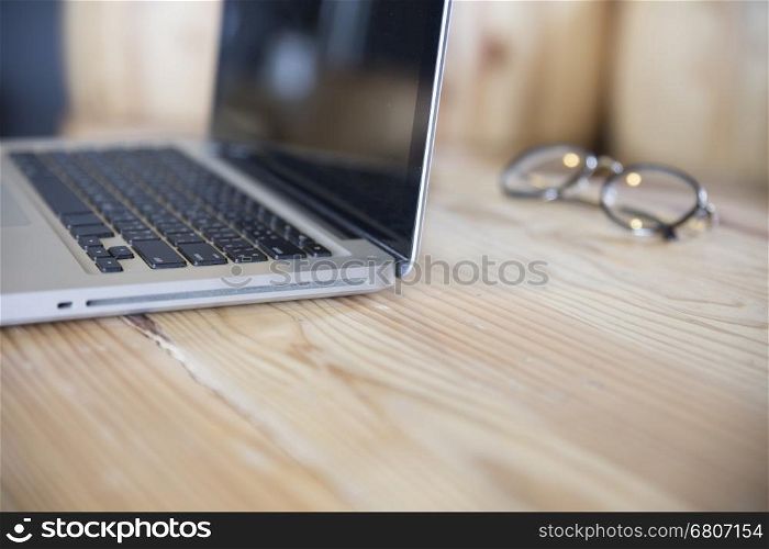 eyeglasses with laptop computer notebook on wooden desk