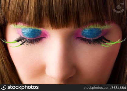 eyes close up of beautiful young woman with green eyelashes and vibrant color