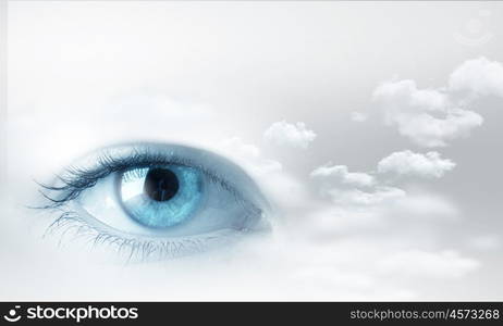 Eyes health. Female blue eye on cloudy sky background